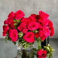 A Moment In Time arrangement with hot pink Ecuadorian roses and scented geraniums in a modern design, available for same-day delivery by Beverly Hills Florist.