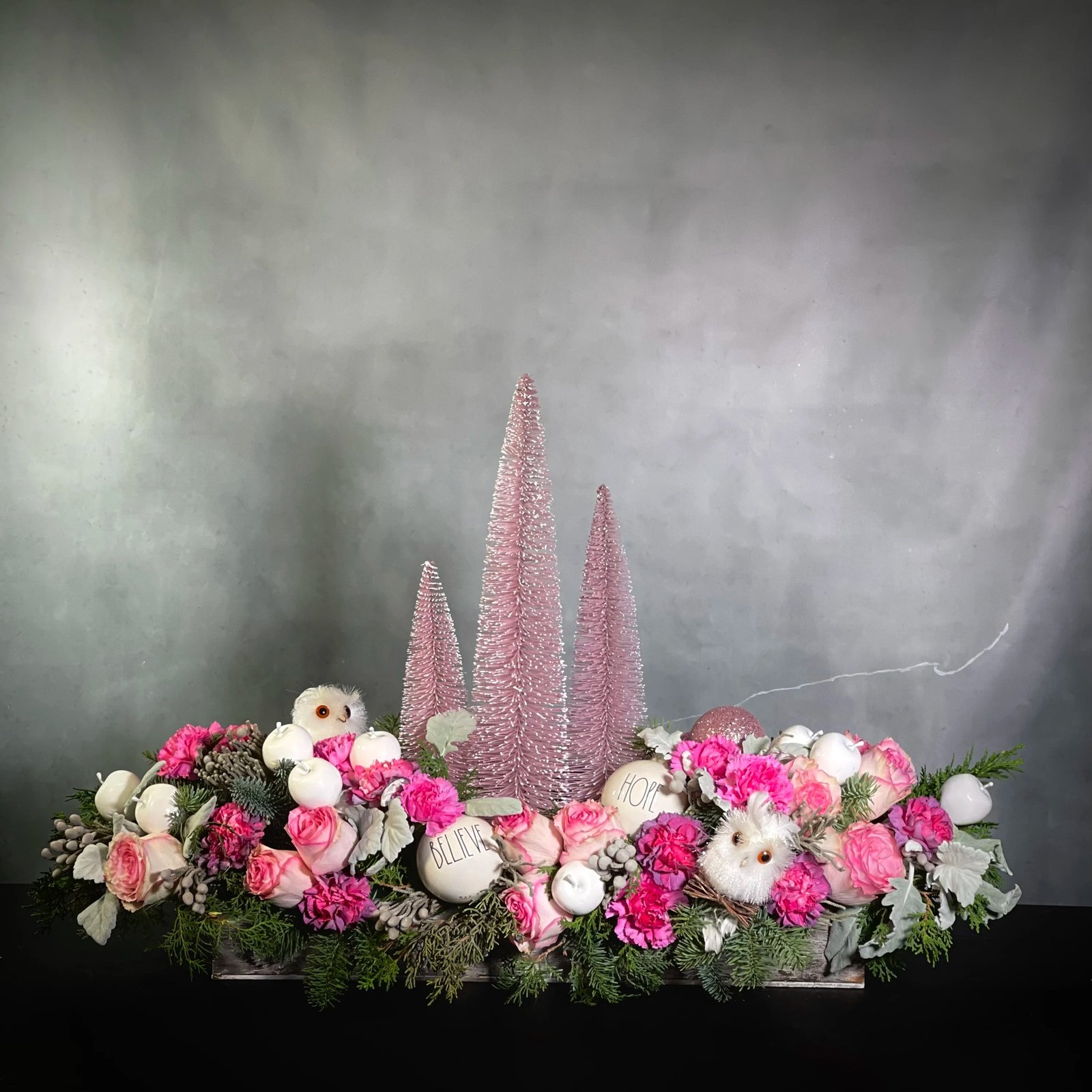 pink-christmas-holiday-floral-arrangement-bh-florist Pink Christmas arrangement featuring orchids, pink peonies, white hydrangeas, and holiday greens in a rectangular ceramic vase, available for same-day delivery by Beverly Hills Florist.